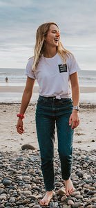 Woman standing and laughing as she walks on the beach with Nöz's orange sunscreen on her nose. 