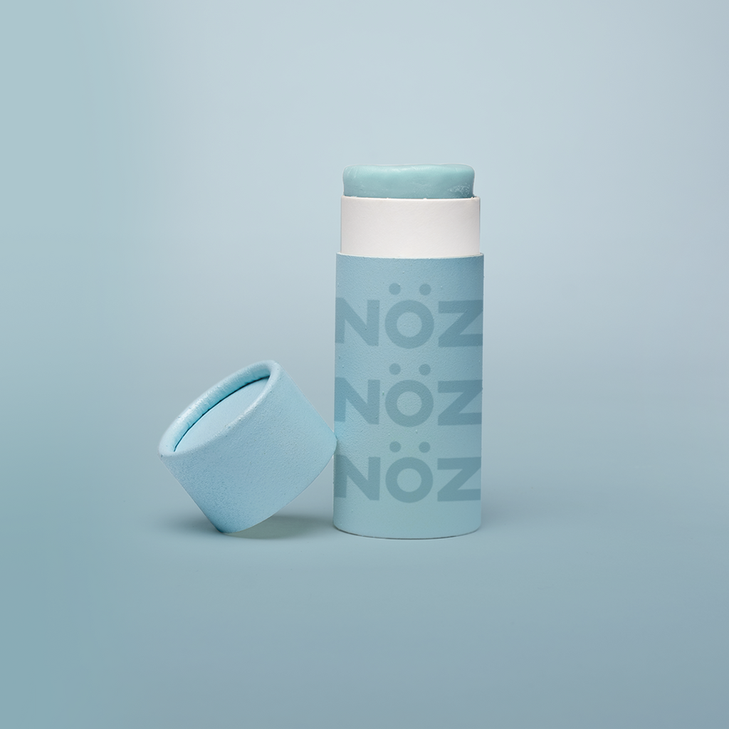 Nöz's light blue sunscreen stick in front of a baby blue background.