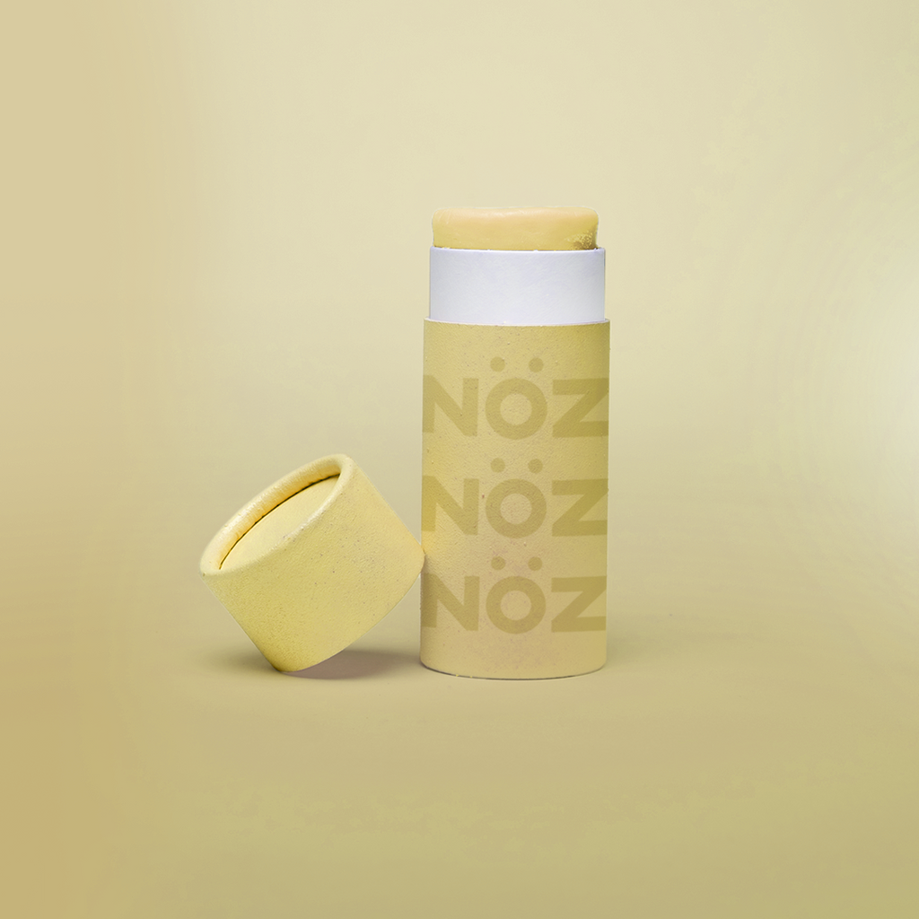 Nöz's yellow sunscreen stick in front of a light yellow background.